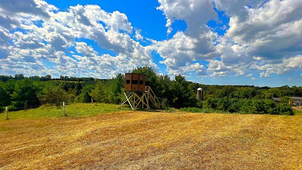 Wooden Hunting Blind in Field Under Cloudy Blue Sky