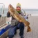 Man Holding Large Fish on Boat Deck Near Ocean